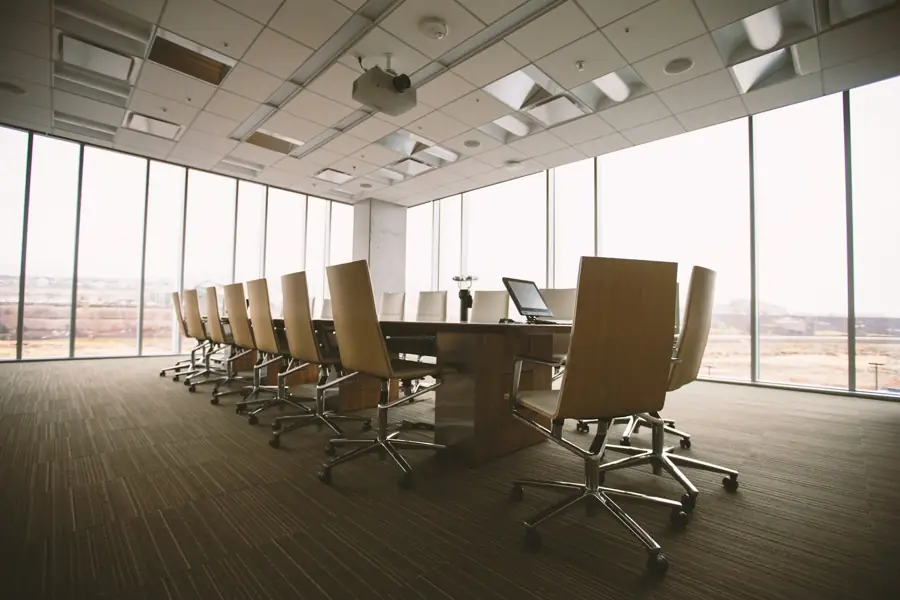 Empty boardroom with a long conference table and windows