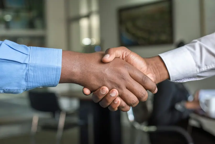 Two professionals shaking hands across a table